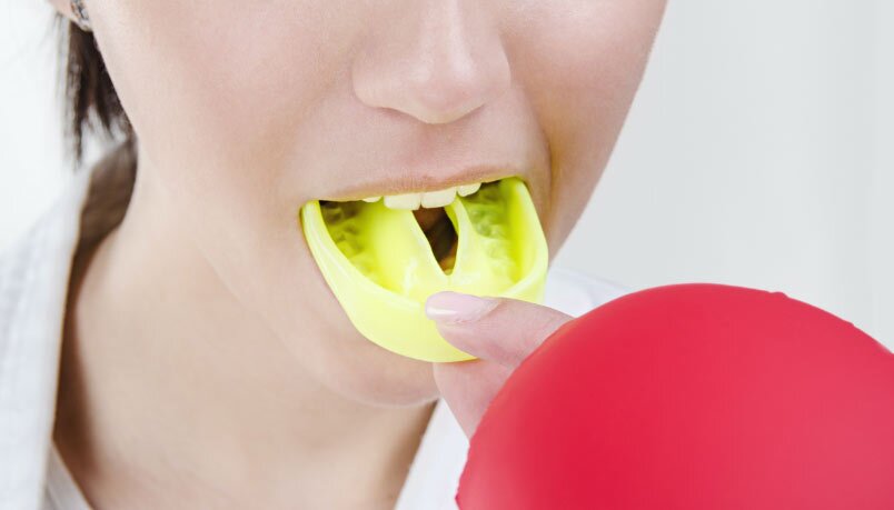 A Woman Putting a Sports Mouthguard Inside Her Mouth